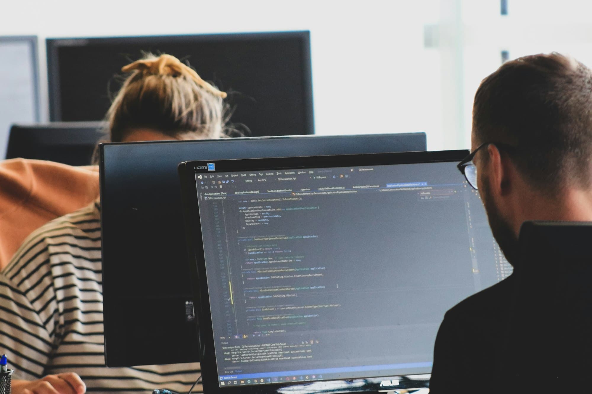 Dos desarrolladores trabajando con código en sus monitores